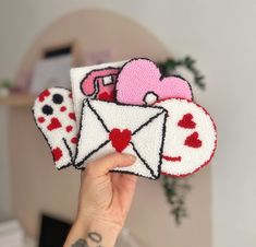 someone holding up two patches with hearts and an envelope