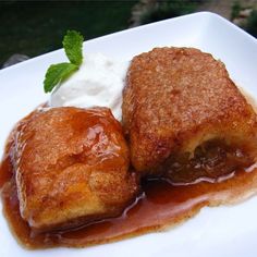 two pastries are sitting on a plate with ice cream and mint sprig