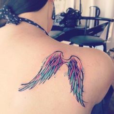 the back of a woman's shoulder with an angel wing tattoo