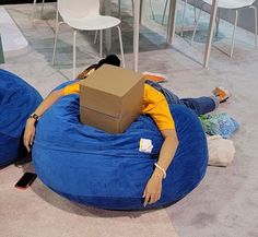 a person laying on a bean bag chair with a cardboard box on top of their head