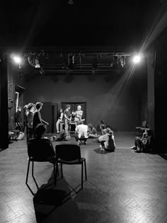 black and white photograph of people sitting on the floor in front of a stage set