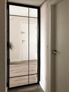 an open door leading to a white room with wood flooring and large glass doors