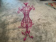 a pink wire mannequin is on the floor next to a carpeted area