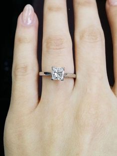 a woman's hand with a diamond ring on top of her left hand,