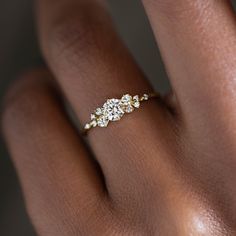 a woman's hand with a diamond ring on top of her finger and two diamonds in the middle