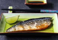 a fish on a plate with chopsticks next to it and a lime slice