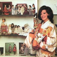 a woman standing in front of shelves with dolls