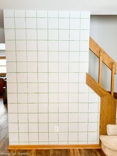 an empty room with white walls and wood flooring in the corner, next to a stair case