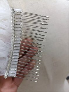 a person holding a comb in their left hand with white fabric on the other side