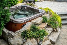 an outdoor hot tub surrounded by rocks and plants