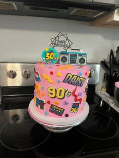 a pink birthday cake sitting on top of a stove