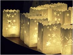 paper bags with white snowflakes are lined up on a shelf in the dark