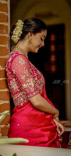 a woman in a red dress leaning against a brick wall