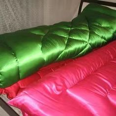 two sleeping bags sitting next to each other on top of a metal bed headboard