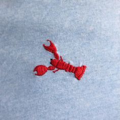 a red lobster embroidered on a light blue shirt