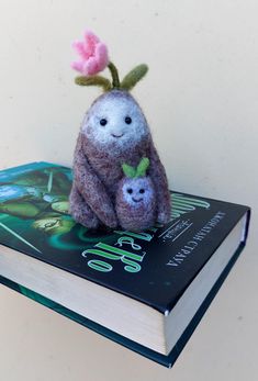 a stuffed animal sitting on top of a book next to a pink flower in it's hair