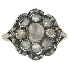 Here we have a wonderful example of Georgian craftsmanship. This multi-layered cluster ring features an oval shaped rose cut diamond at the centre which is circulated by a slightly smaller array of matching rose cut diamonds. Multiple convex motifs make up the frame to the outer exterior; each of which is set with a trio of tiny rose cut diamonds. All stones here are set in silver on a closed gold backing; a feature typical of the period, however, the neatly engraved patterned band has been crafted entirely from 15ct yellow gold. Condition: Used (Very Good) Weight: 3.8 grams Size: K (50) Face Dimensions: 16mm x 15mm Band Width: 1mm Centre Diamond Weight: Approx. 0.30ct (spreads 0.50ct) Remaining Diamond Weight: Approx. 0.42ct Tested As: 15ct Gold & Silver Period: Georgian Box: The Vintage Face Dimensions, Diamond Cluster Ring, Diamond Cluster, Rose Cut Diamond, Cluster Ring, Ring Box, Rose Cut, Silver Gold, Diamond Cuts