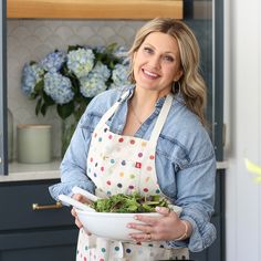 a woman in an apron holding a bowl of salad