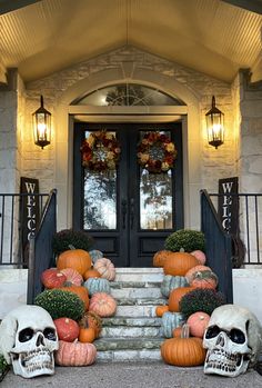 halloween decorations on the front steps of a house with skulls, pumpkins and gourds