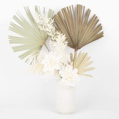 a vase filled with white flowers and palm leaves