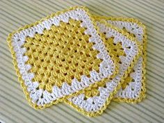 three yellow and white crocheted coasters sitting on top of a striped tablecloth