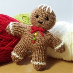 a brown teddy bear sitting next to a ball of yarn on top of a wooden table