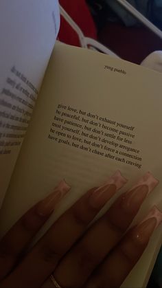 a woman reading a book with her nails on top of the book's pages