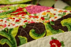 a close up view of a quilted table runner with flowers and leaves on it