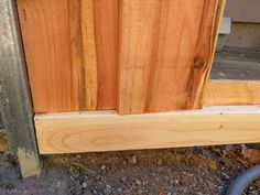 a close up of the side of a wooden door frame with metal pipe running through it