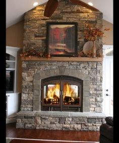 a living room with a fire place in the center and a ceiling fan above it