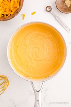 a bowl filled with yellow liquid next to other ingredients