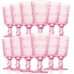 six pink glass goblets are lined up in a row on a white background