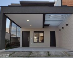 the front entrance to a modern house with black shutters and an open patio area