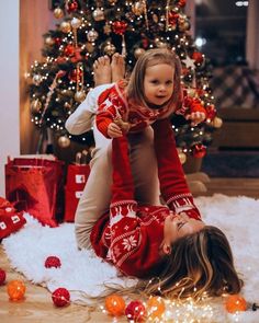 a woman and child laying on the floor in front of a christmas tree