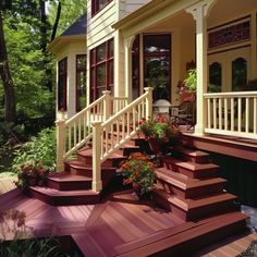 a porch with steps leading up to the front door and flowers in pots on the side