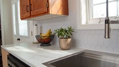 a kitchen counter with a bowl of bananas and a basket of fruit on the sink