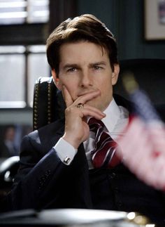 a man in a suit and tie sitting at a desk with his hand on his chin