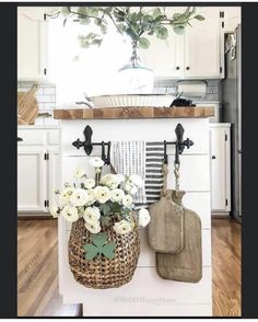 a kitchen with white cabinets and an orange arrow pointing to the center island that has flowers in it