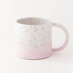 a white and pink coffee mug with speckles on it's side, against a white background