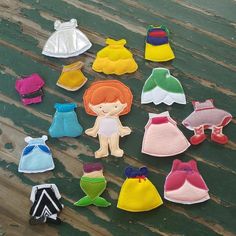 there are many small felt doll clothes on the table with each one's own