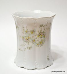 a white vase with yellow flowers painted on the outside and inside, sitting on a white surface