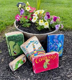 there is a potted plant with flowers in it and four books on the ground