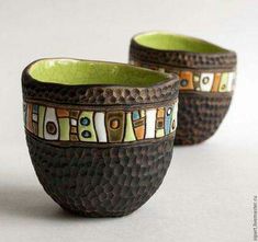 two brown and green bowls sitting next to each other on top of a white table