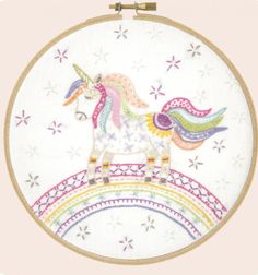 an embroidery kit with a unicorn on top of a rainbow - shaped object in the shape of a circle