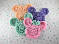 three crocheted mickey mouse coasters sitting on top of a polka dot tablecloth