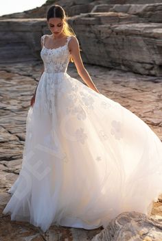 a woman in a wedding dress standing on rocks