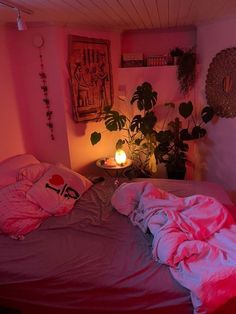 a bed with pink sheets and pillows in a room next to a potted plant