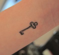 a small key tattoo on the wrist