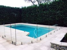 an empty swimming pool with glass fencing around it and stone steps leading up to the pool