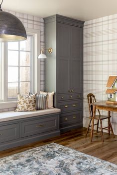 a window seat in the corner of a room next to a table and chair with pillows on it